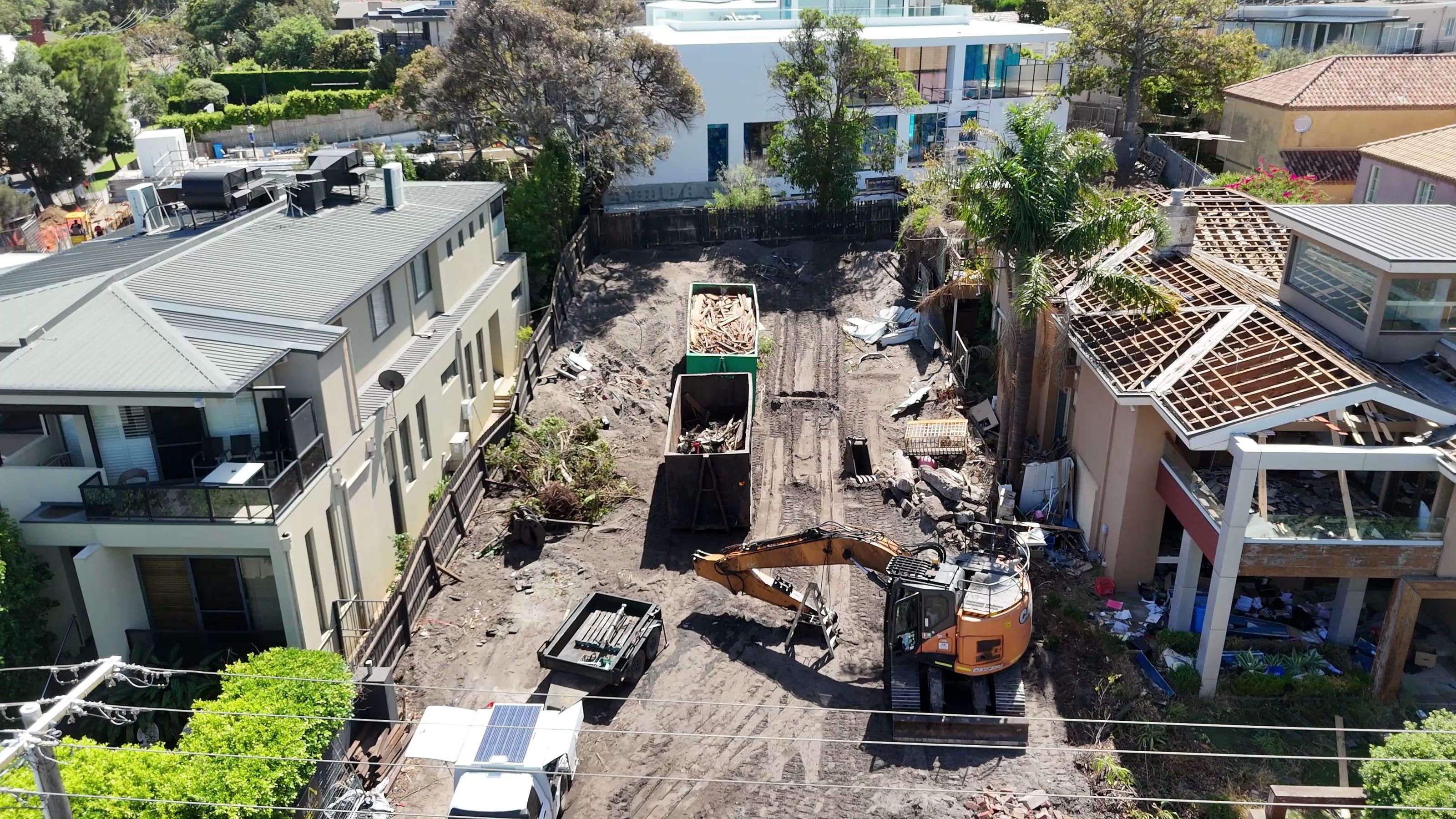 Aerial view of demolition underway, with an excavator clearing the site