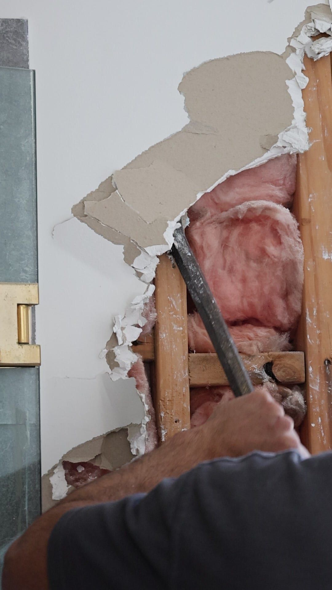 A wall lining removed to reveal the timber framing and insulation behind