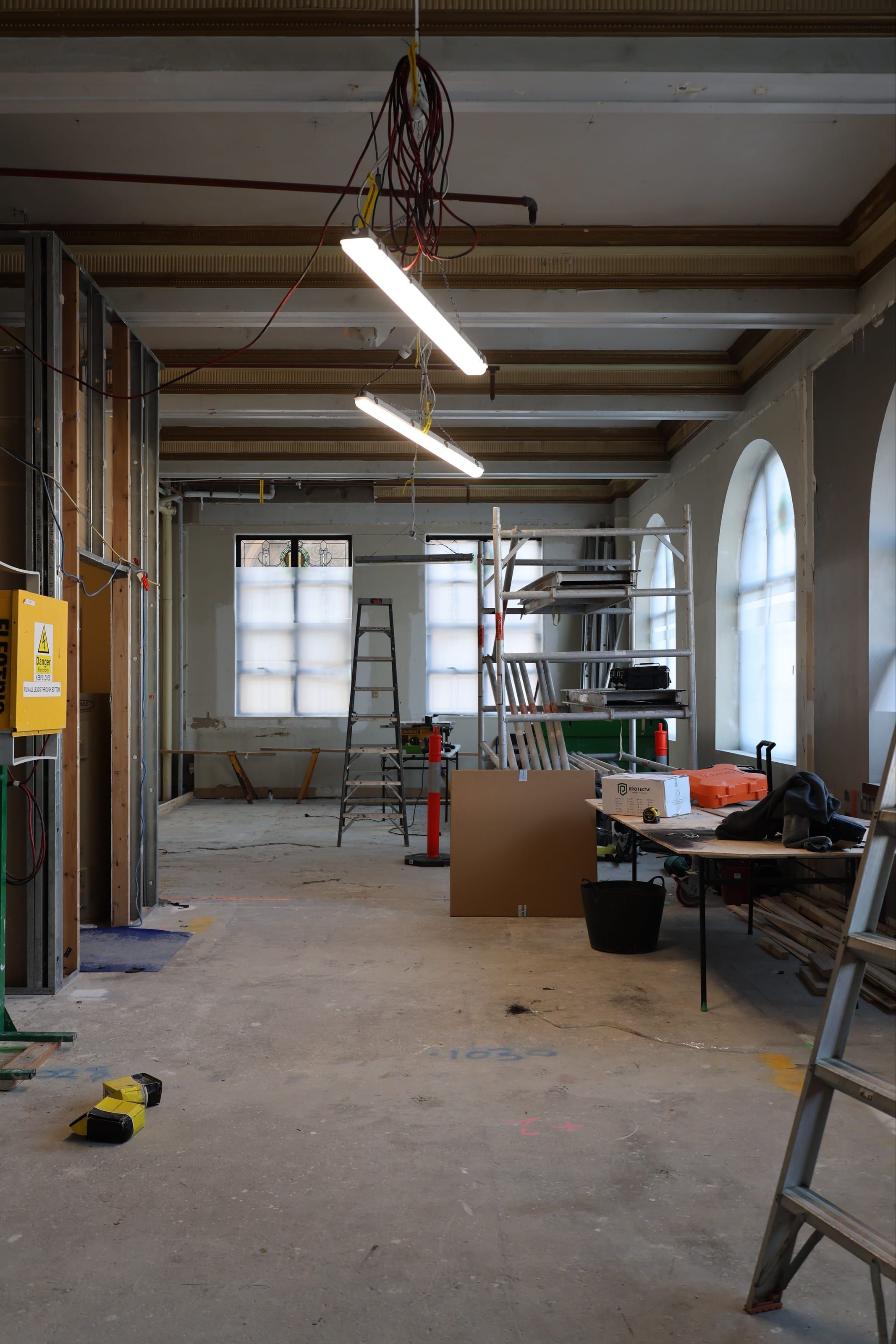 The fit-out underway, with scaffold, benches and materials across the open floor