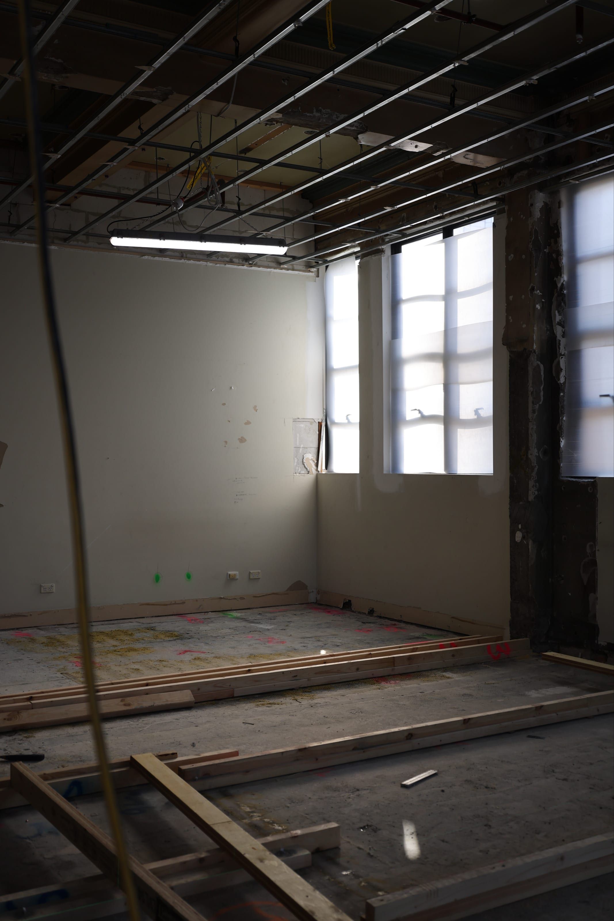 New timber floor framing set out across a stripped-back room beneath an exposed ceiling